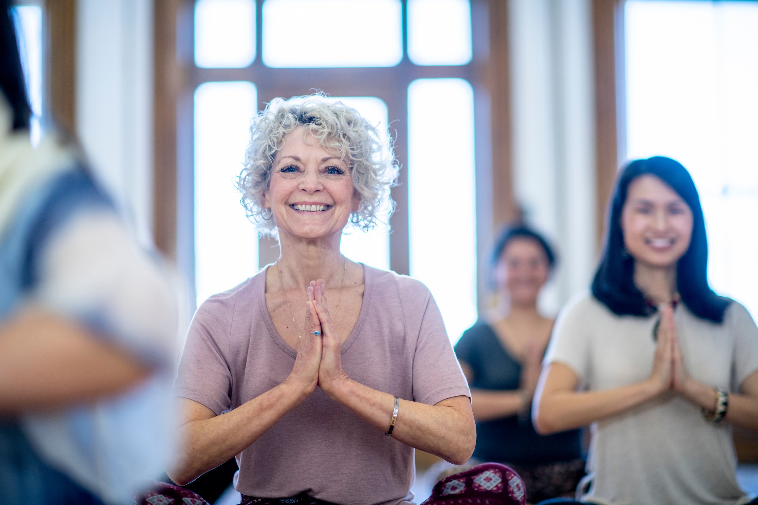 Older woman smiles while doing yoga